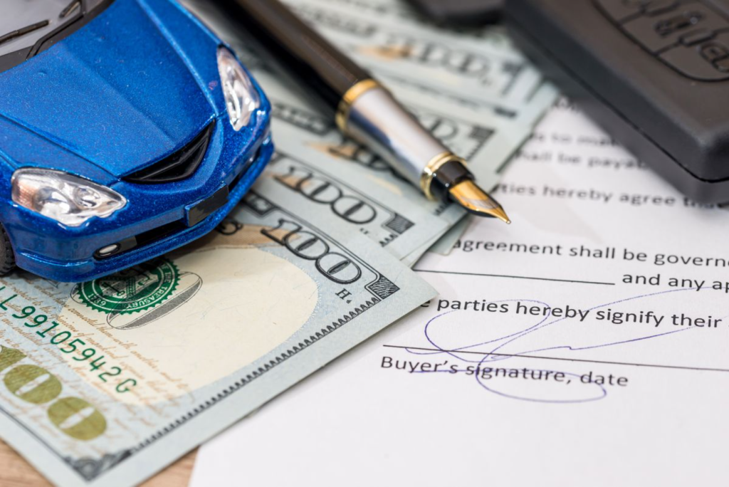 The image shows a toy car, money, a pen, and a contract with a buyer's signature.