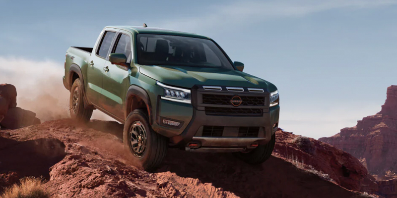 A Nissan Frontier pickup truck driving over rocky terrain.